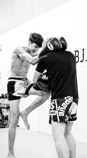 Muay Thai student throwing a knee strike during pad work in Mission, BC